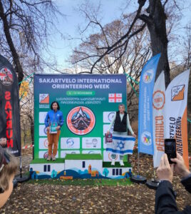 לודמילה גלוזשטיין על הפודיום בטביליסי, מחייכת עם המדליה אחרי שבוע של תחרויות ניווט בגאורגיה