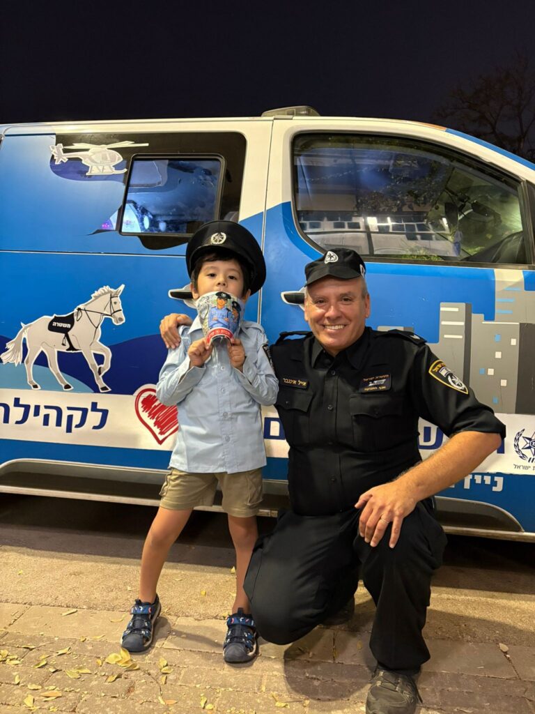 ילדים עם צרכים מיוחדים בגבעת שמואל עומדים נרגשים לצד ניידת המשאלות של משטרת ישראל, עם חיוך רחב וכובעי שוטר כחולים