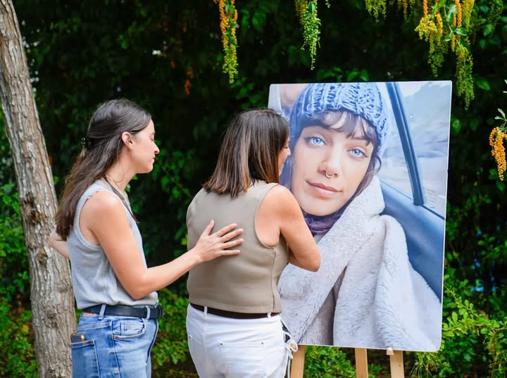 אמה של יובל מול התמונה וספסל הנצחה חדש בפארק ברמת גן, עליו לוחית עם שמה וסיפור חייה.