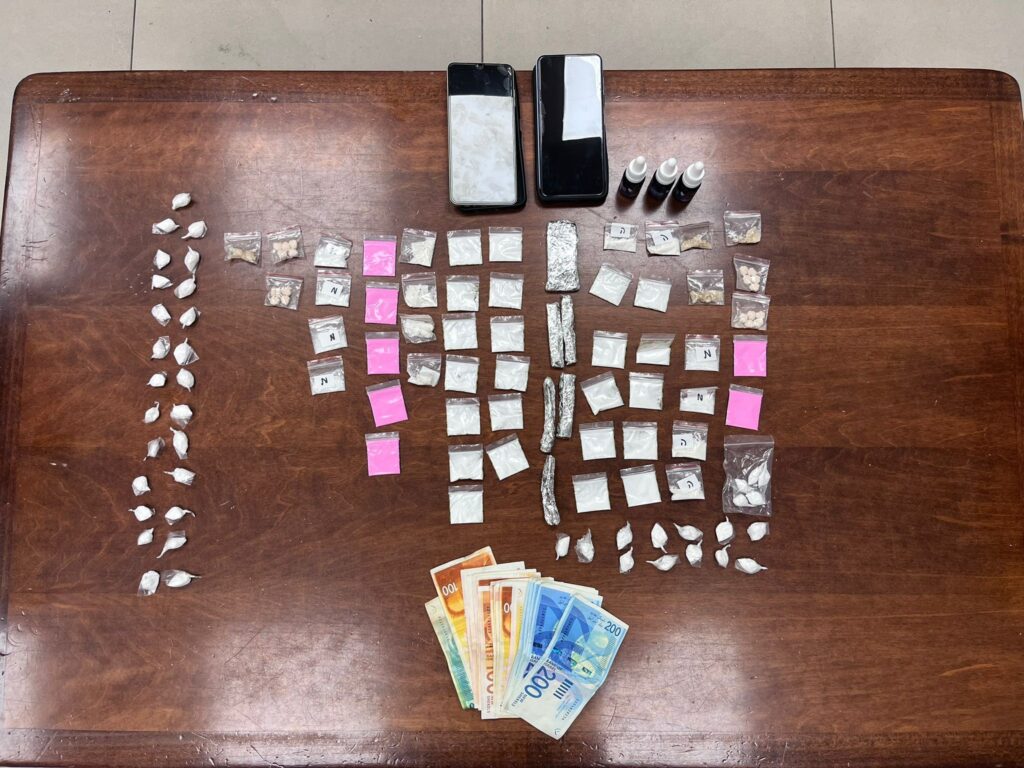 שקיות סמים, כדורי אקסטזי וכסף מזומן שהונחו על שולחן בחדר חקירות - כפי שנתפסו ברכב החשוד בחולון