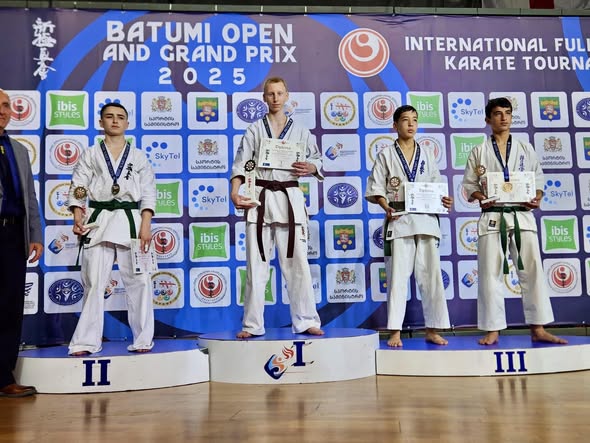 ספורטאי מועדון "אשקלון פאוור" על הפודיום מחזיקים גביעים ומדליות, דגל ישראל פרוס מאחוריהם. רגע של גאווה