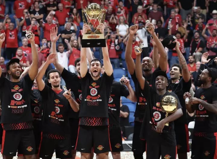 שחקני הפועל ירושלים מניפים את גביע ווינר על הפרקט בירושלים, עטופים באוהדים באדום