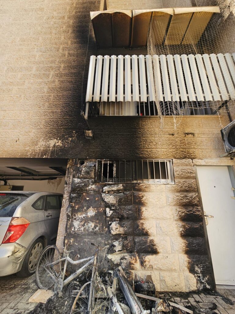 כניסה לבניין מגורים בבית שמש. סימני פיח סביב הדלת וכוחות משטרה ותיעוד של הזירה