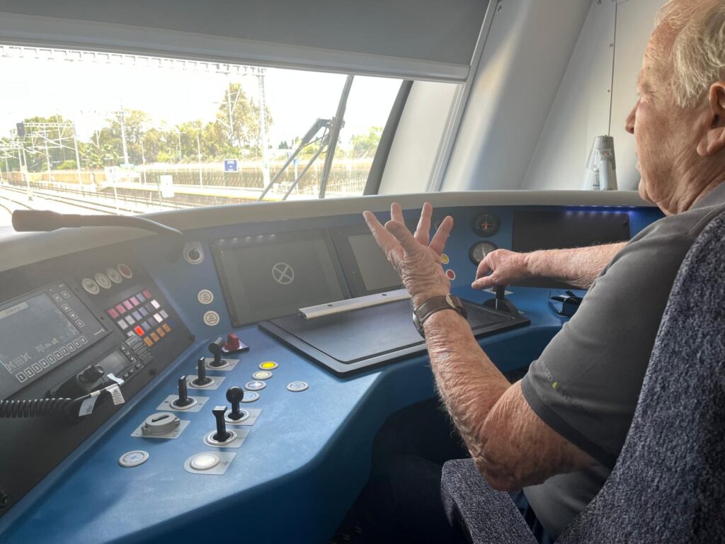 אריה עינב בן ה־80 מרעננה בתא הנהג של רכבת ישראל, לצד נהג הרכבת ולוחם המילואים אורן דה פז.