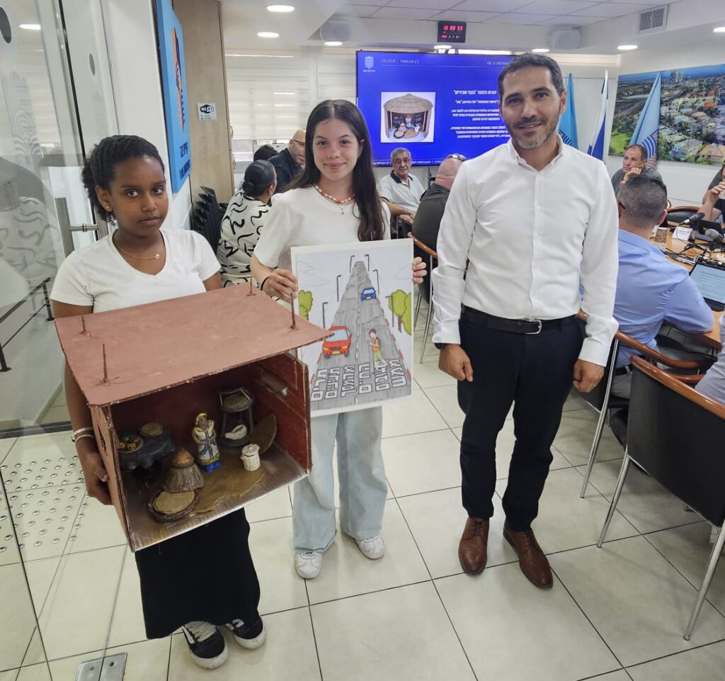 לפעמים גאווה עירונית מתחילה בשתי תלמידות צעירות שמזכירות לכולם שחינוך טוב לא מסתיים בכיתה - הוא מגיע גם לבמה של מועצת העיר.