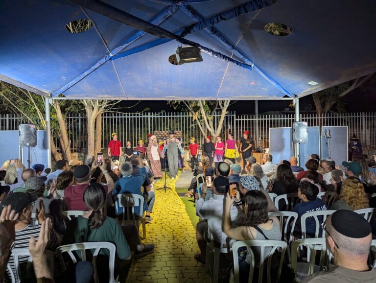 ילדים ובני נוער עולים מופיעים על הבמה במחזמר "הקוסם מארץ עוץ" מול אולם מלא במודיעין מכבים רעות.