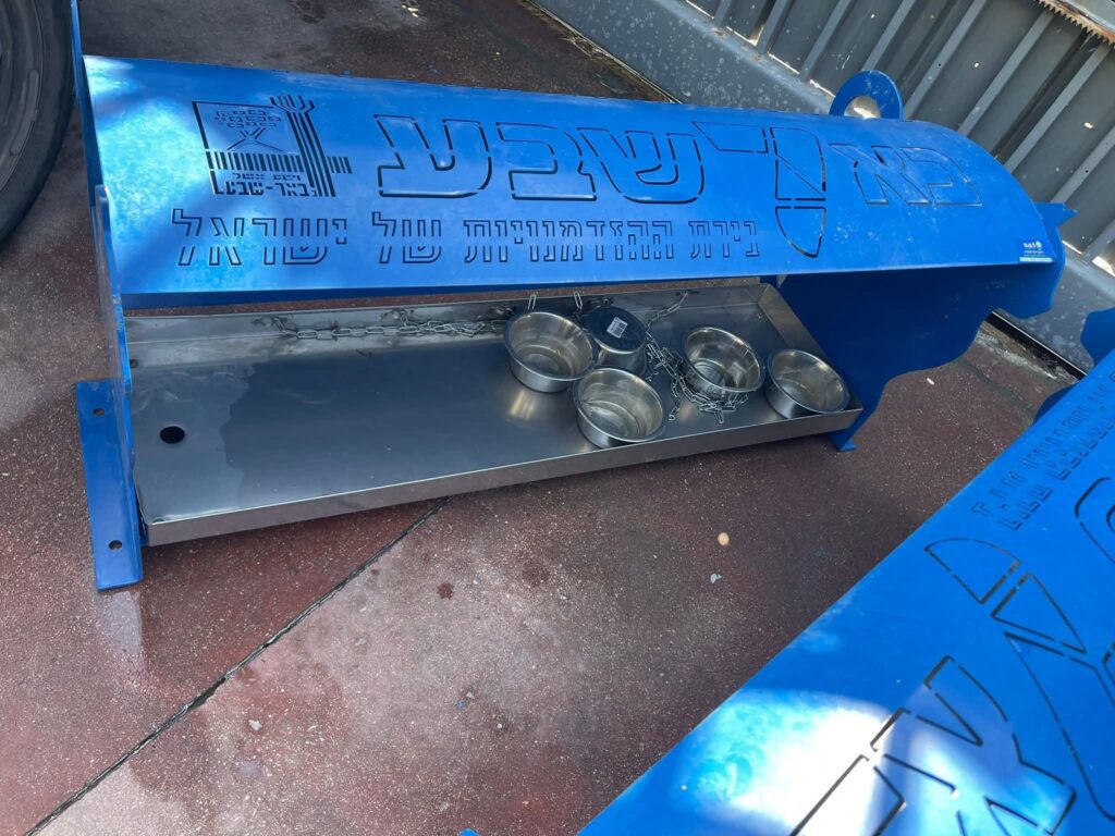 פינת האכלה מוסדרת לחתולי רחוב בבאר שבע, עם מתקני מזון ומים מסודרים במרחב ציבורי נקי ומטופח.