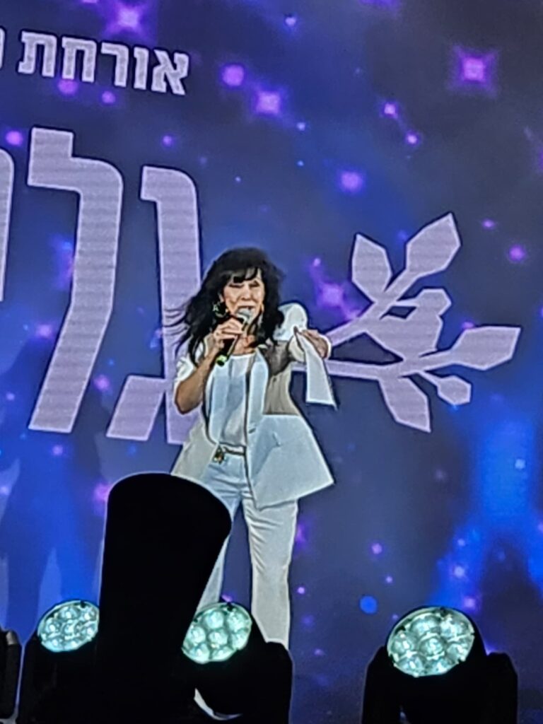 גלי עטרי על במת אירוע הוויגסטוק בתל אביב, מקבלת את מגן הזהב של הקהילה הגאה מול קהל גדול ומלכות דראג במסגרת שבוע הגאווה