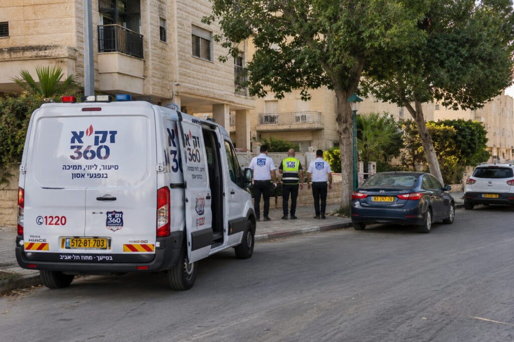 ניידת חירום עומדת ברחוב שקט ביבנה בשעות הבוקר, סמוך לבניין מגורים שבו פועלים צוותי סיוע