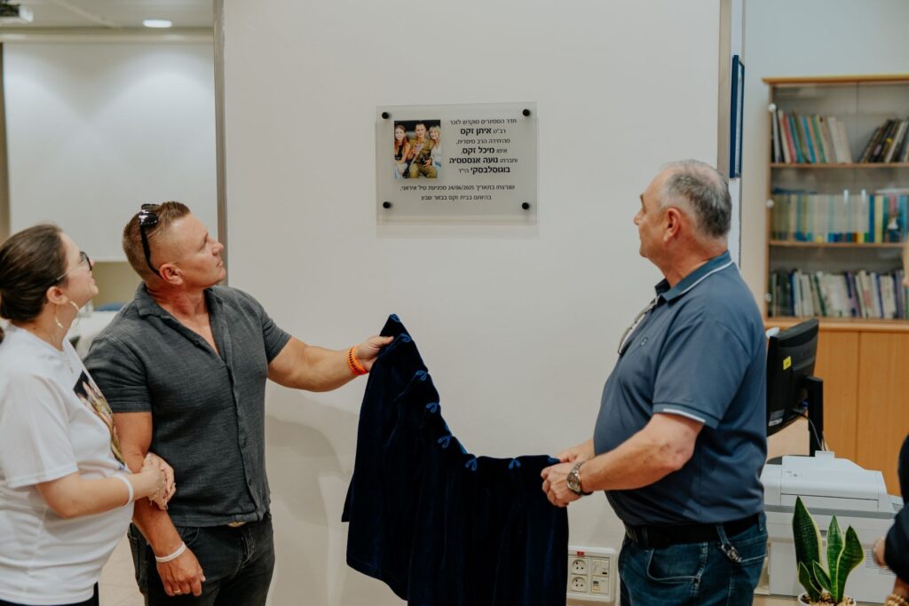 חדר סמינרים חדש במרכז הרפואי סורוקה, עם שולחן ישיבות, כסאות, מסך מצגות ושלט הנצחה צנוע לזכר ההרוגים