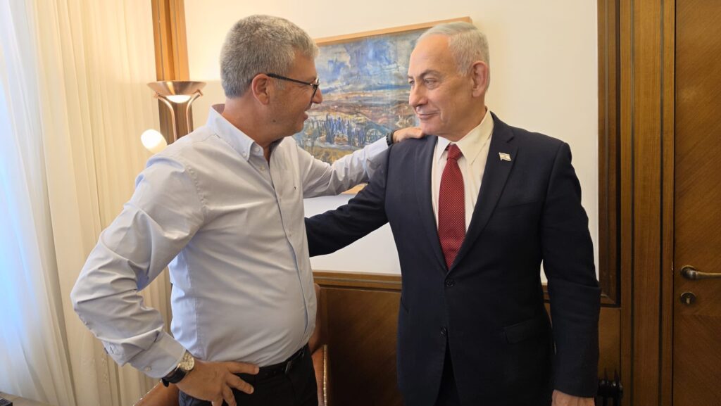 ראש עיריית רמלה וראש הממשלה לוחצים ידיים בפגישה רשמית, כשברקע דגלי ישראל ואווירה ממלכתית.