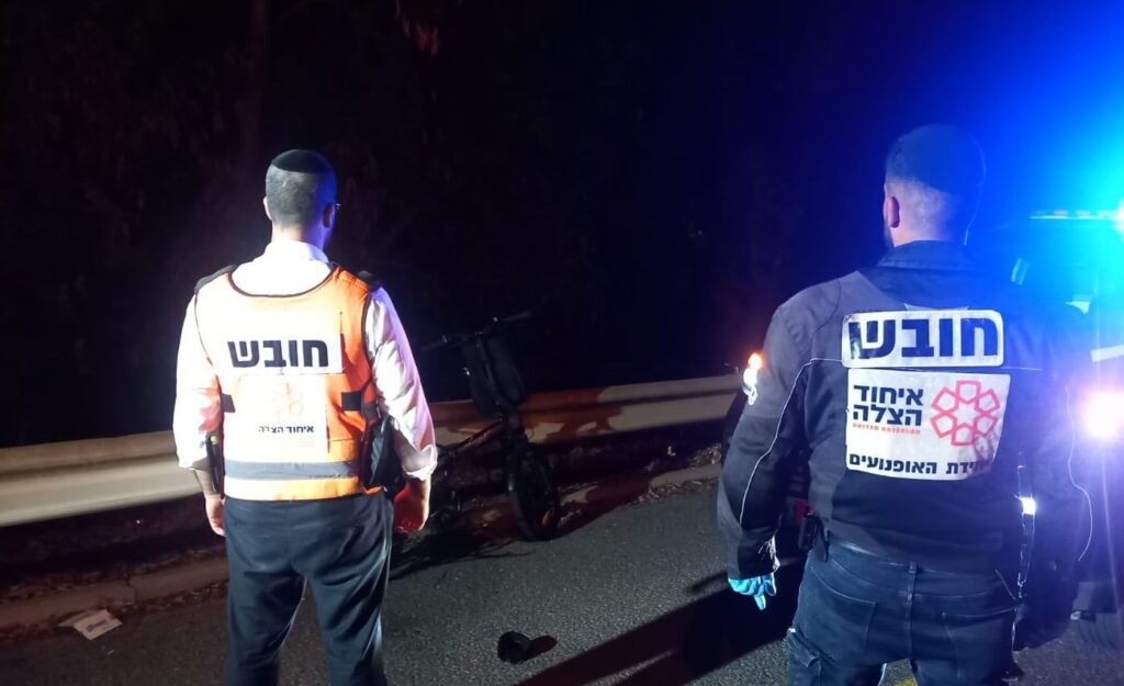 כוחות הצלה מעניקים טיפול לרוכב אופניים חשמליים בזירת תאונה לילית ברחוב עירוני בנתניה, לצד רכב מעורב וצוותי חירום הפועלים במקום
