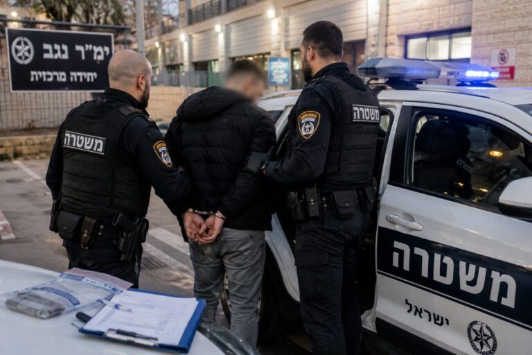 שוטרים עוצרים חשוד במהלך פעילות מבצעית בבאר שבע, לצד ניידת משטרה, אזיקים ומסמכי חקירה הקשורים לעבירות סחיטה והלוואות בשוק האפור