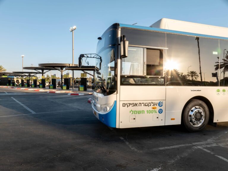 אוטובוס לילה מואר עוצר בתחנה מרכזית בעיר בשעות הערב, כאשר צעירים וצעירות עולים לנסיעה בדרכם לאזורי בילוי, על רקע אורות העיר ואווירת קיץ תוססת
