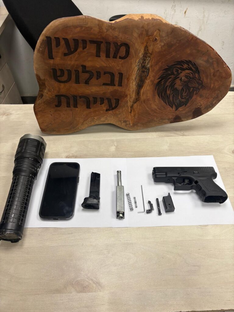 אקדח, מחסנית וציוד שנתפסו במהלך פעילות משטרתית סמוך למעבר מיתר, לצד ניידת משטרה וכוחות בשטח