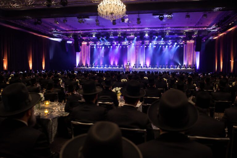 הרב יצחק ורדי עומד לצד הרבנים הראשיים לישראל במהלך טקס ההכתרה, כשהוא עטוף בטלית חדשה ומוקף ברבנים, אישי ציבור ותושבי קריית אונו באווירה חגיגית ומרגשת