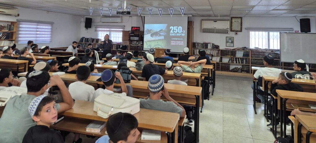 כבאי מסביר לתלמידי תיכון באשקלון על הסכנות בטעינת סוללות ליתיום, במסגרת פעילות הסברה מיוחדת לקראת החופש הגדול