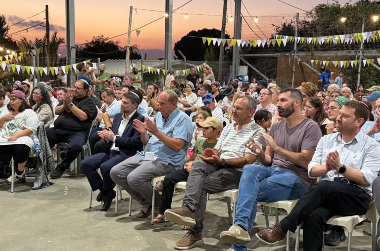 תושבים ומשפחות בטקס הסדרת היישוב גבעות בגוש עציון, על רקע במת האירוע והנוף ההררי של האזור