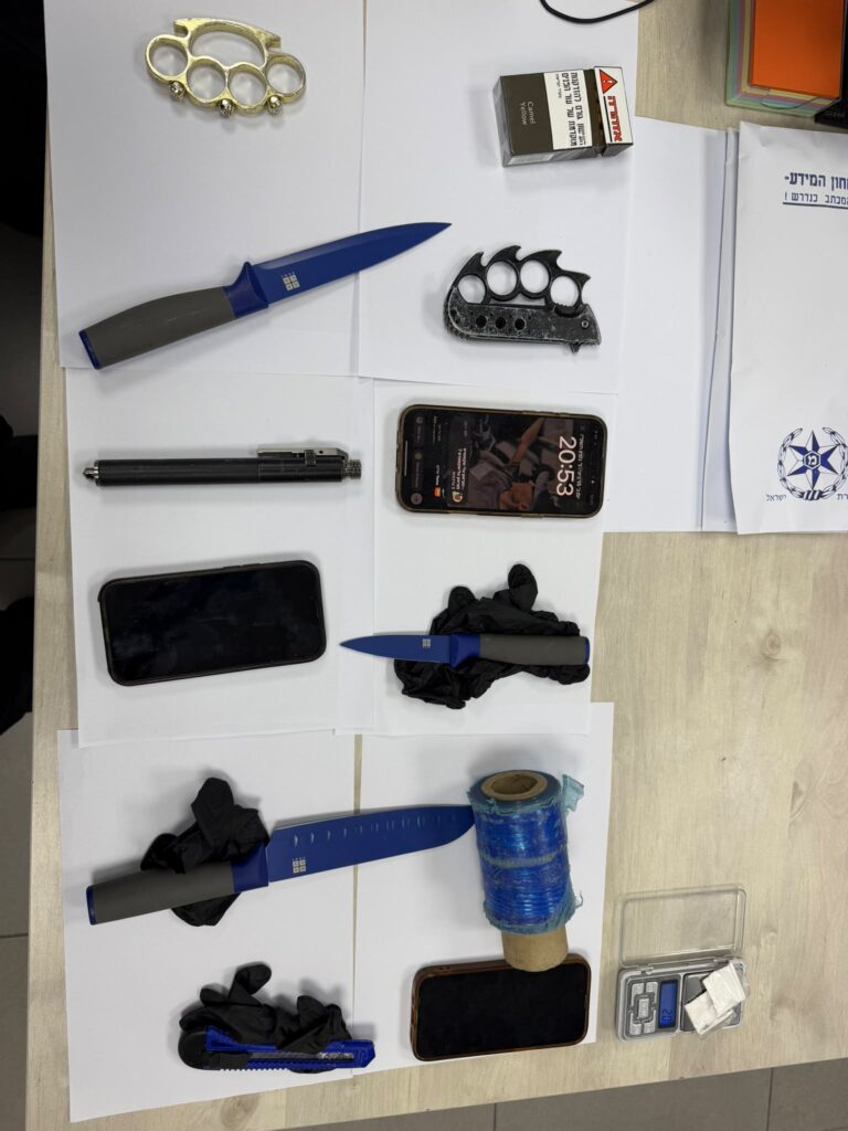 כלי תקיפה שנתפסו ברכב החשודים באשקלון, בהם סכינים ואגרופן, לצד ניידת משטרה וכוחות שפעלו בזירה