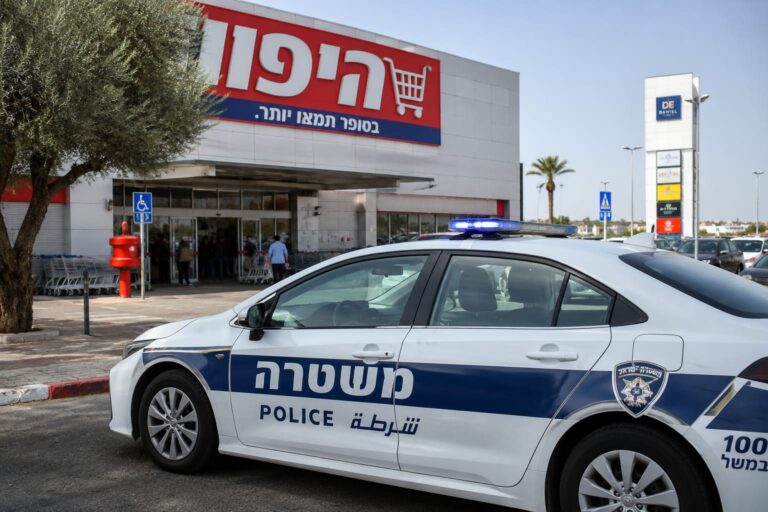 ניידת משטרה מחוץ למרכז מסחרי באופקים, על רקע סופרמרקט עירוני, במסגרת דיווח על כתב אישום שהוגש בעקבות אירוע תקיפה שהתרחש במקום