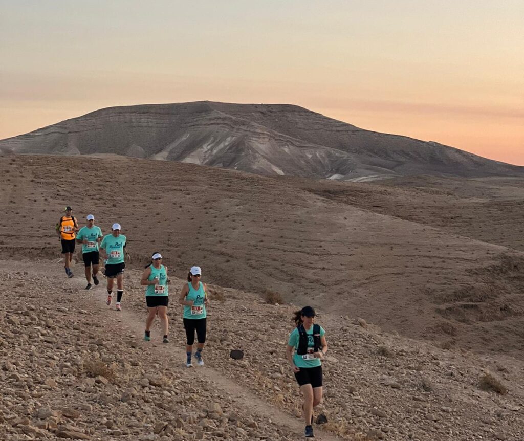 רצים במדבר יהודה בשעת זריחה על רקע מצדה ונופי המדבר
