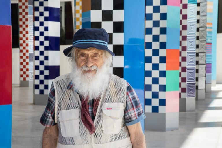 יעקב אגם לצד אחת מיצירותיו הצבעוניות והקינטיות במוזיאון אגם בראשון לציון