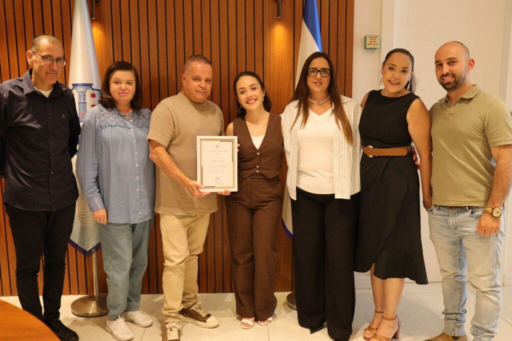 עמית יפרח מנגנת בכינור במהלך הופעה, על רקע אולם קונצרטים, לאחר זכיותיה בתחרויות בינלאומיות והזמנתה להופיע בקרנגי הול בניו יורק