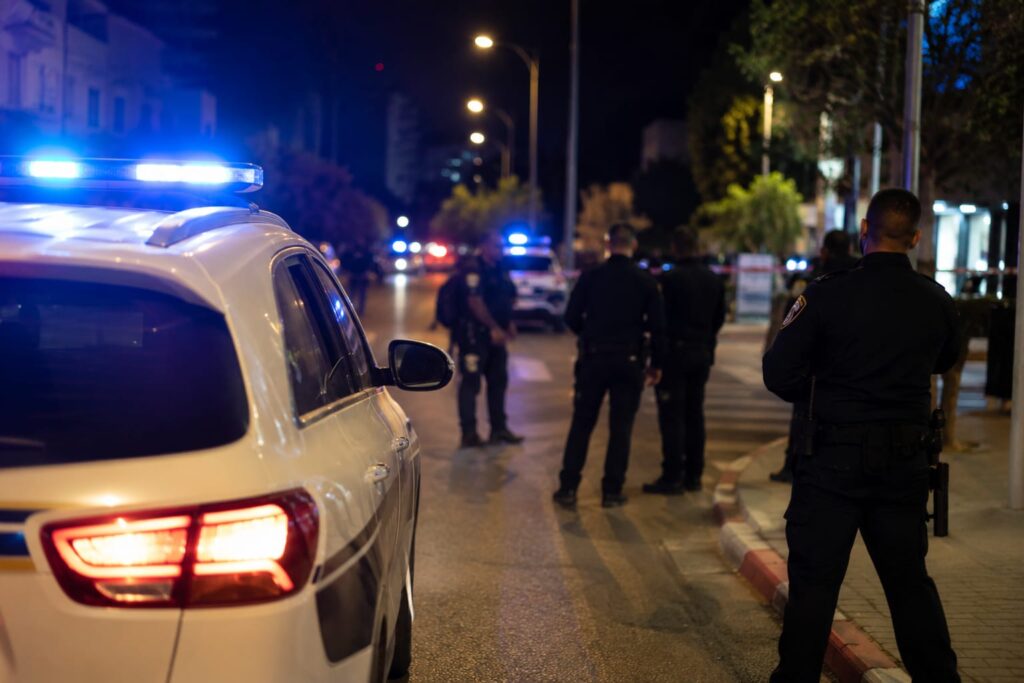ניידת משטרה וכוחות משטרה פועלים בזירת אירוע אלימות בעיר בשעות הלילה