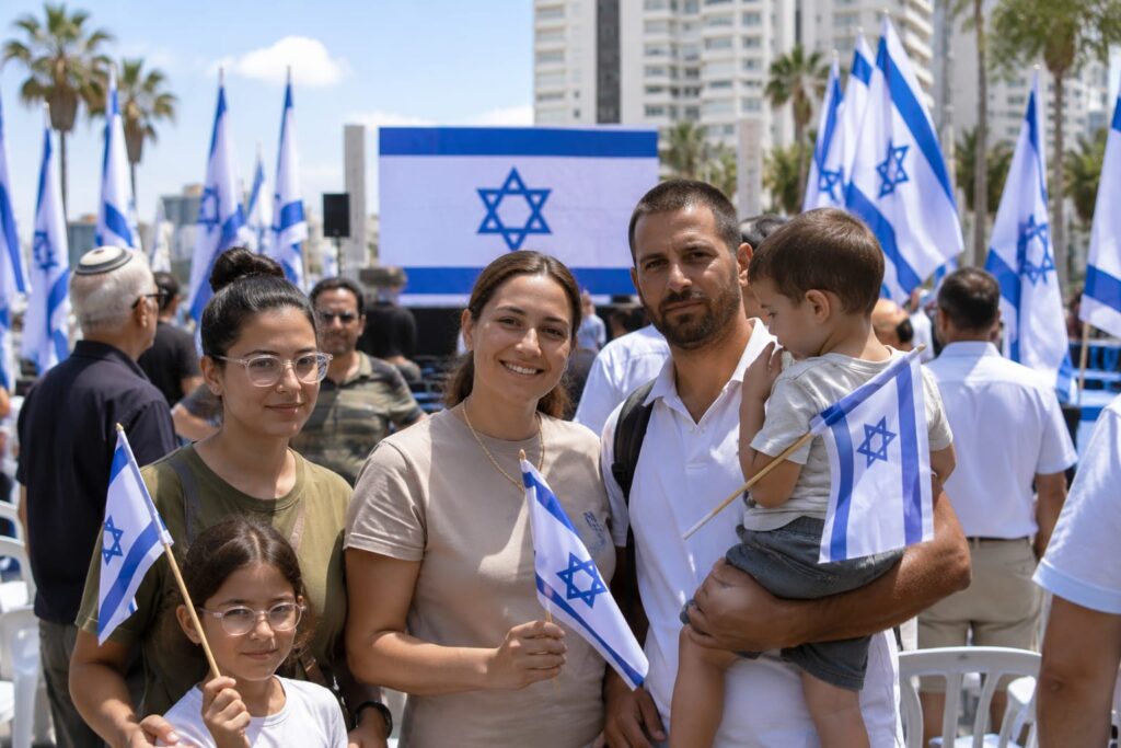עולים חדשים לצד דגלי ישראל בטקס קבלת פנים, על רקע נתוני העלייה החדשים בבת ים
