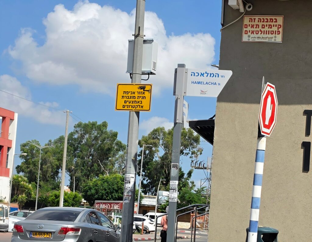 מצלמת אכיפה עירונית המוצבת מעל רחוב מרכזי בקריית מלאכי, כשברקע כלי רכב, מדרכה ואזור חנייה מסומן