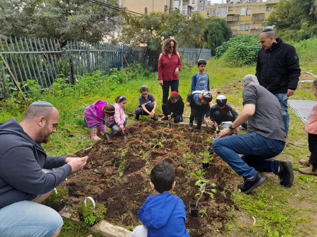 משפחות וילדים בפעילות קטיף בגינה קהילתית ברחובות
