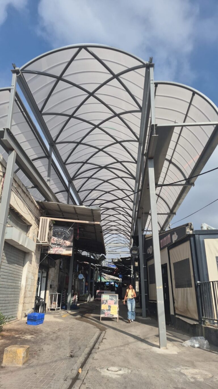 התקנת לוחות הקירוי מעל דוכני שוק רמלה בזמן שהמסחר ממשיך לפעול