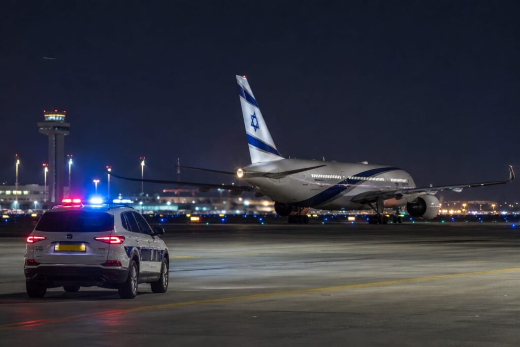 אילוסטרציה של מטוס נוסעים על מסלול ההמראה בנתב"ג ולצדו ניידת משטרה