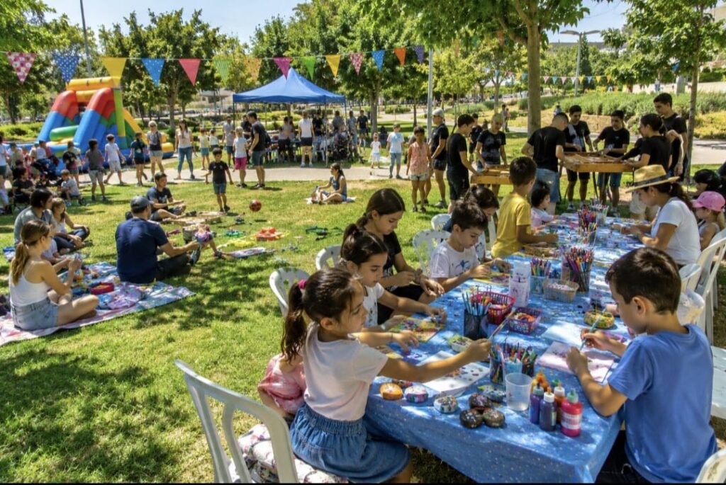 קיץ צבעוני של משפחות וילדים בפעילות קהילתית בפארק, לצד בני נוער בפעילות ומתחם יצירה