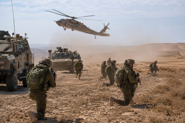 כוחות צה"ל בתרגיל צבאי במרחב פתוח באזור רמת הנגב, כלי רכב צבאיים, מסוק צבאי ברקע וענני אבק